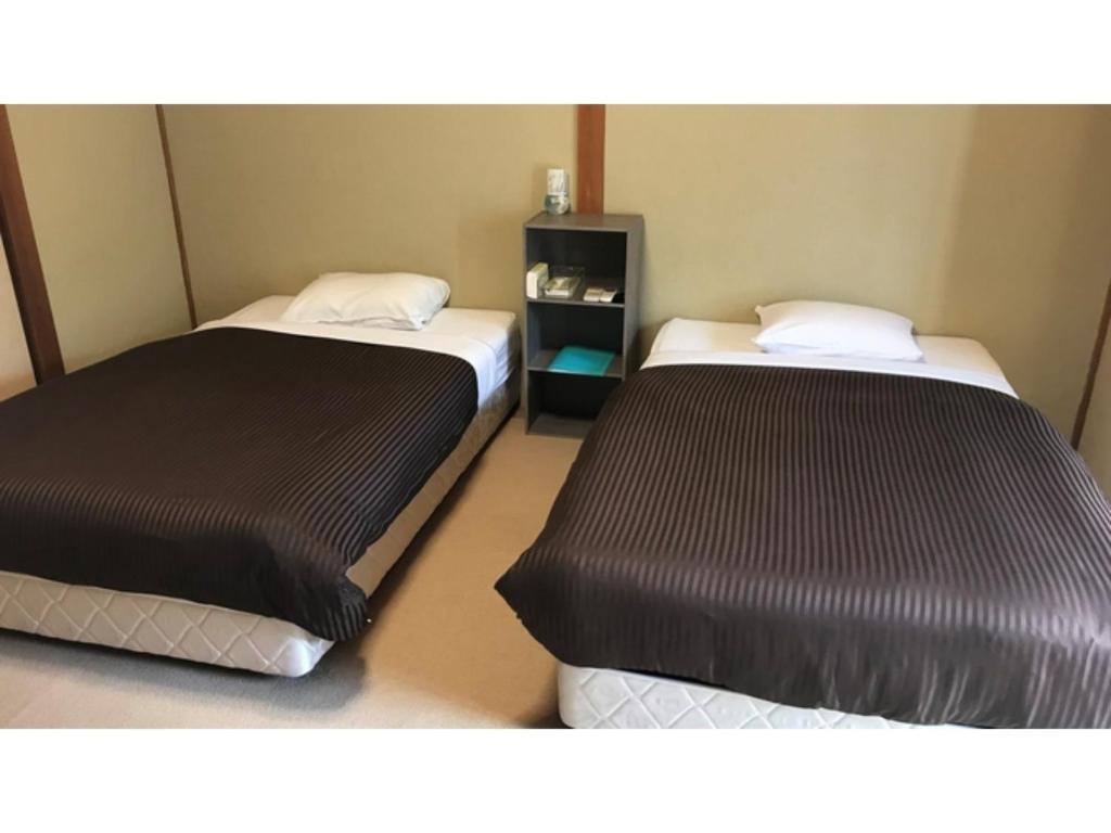 2 letti in una piccola camera con gonne di Biz Hotel Kiyura - Vacation STAY 93179v a Yura