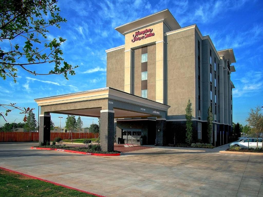 een hotelgebouw met een parkeerplaats ervoor bij Hampton Inn & Suites-Moore in Moore