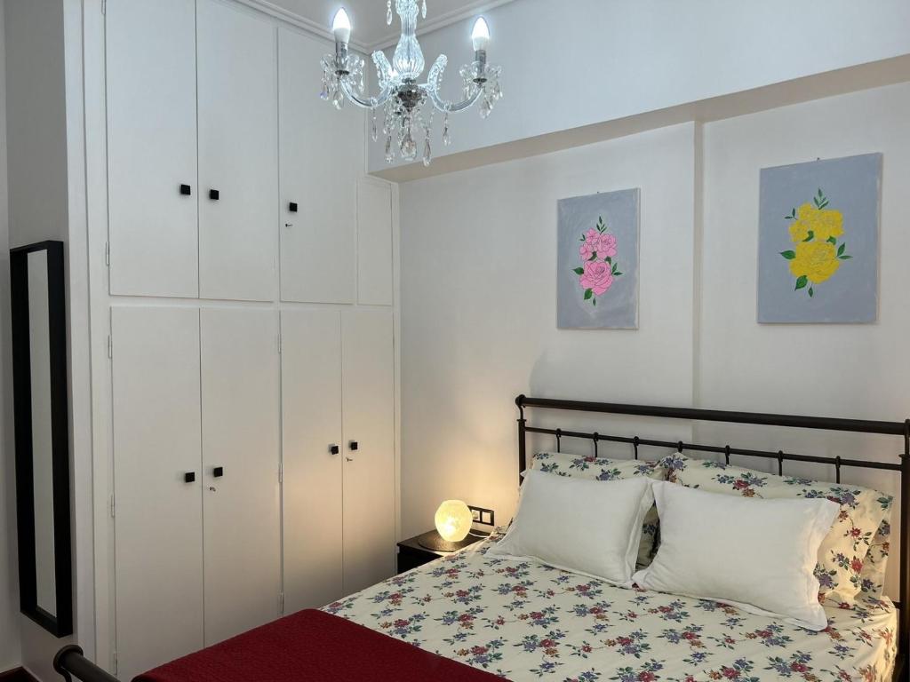 um quarto com uma cama com armários brancos e um lustre em Como la flor, Gizi Attikis em Atenas