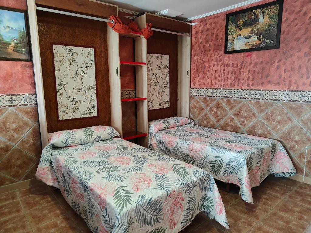 two beds in a room with pink walls at Apartamentos Matraca in Villamediana de Iregua