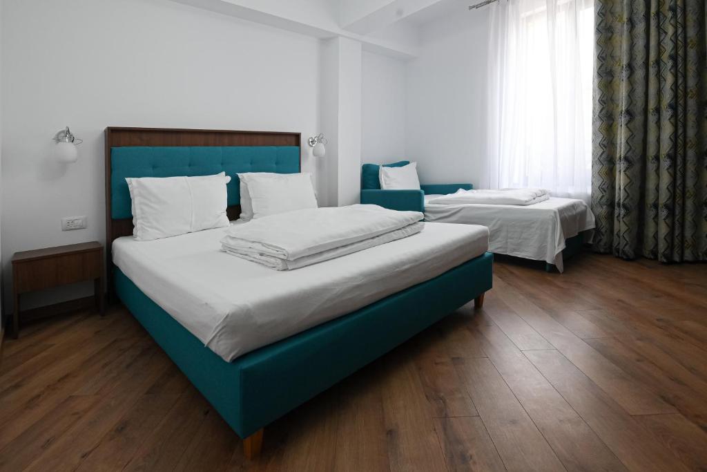 2 łóżka pojedyncze w pokoju z drewnianą podłogą w obiekcie Helios w mieście Sulina