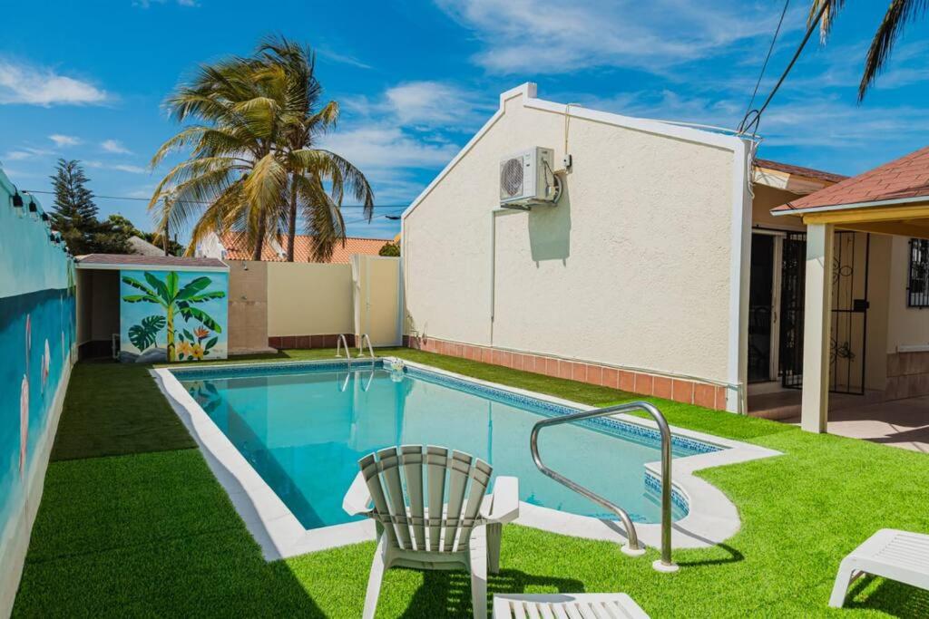 a swimming pool with a chair next to a house at Blue Sky Residence Aruba in Savaneta