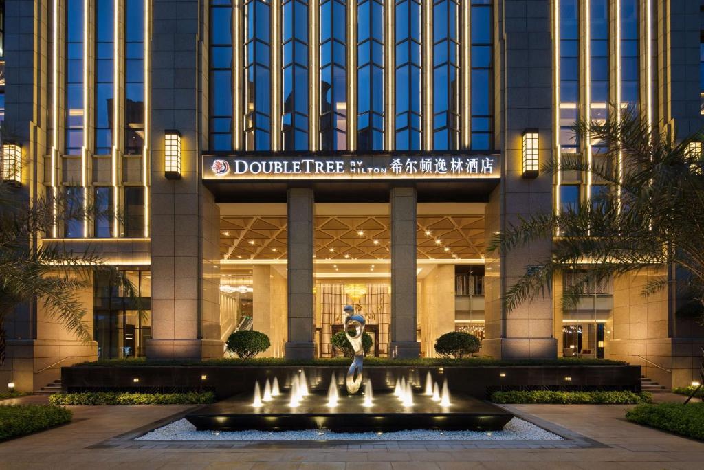 a woman standing in front of a building with a fountain at DoubleTree By Hilton Xiamen-Haicang in Xiamen