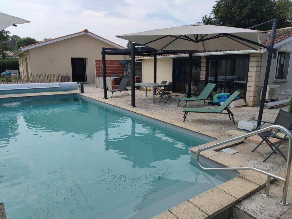 uma piscina com um guarda-sol e cadeiras e uma mesa em 2 Maisons de 3 et 2 chambres avec grande piscine commune em La Teste-de-Buch