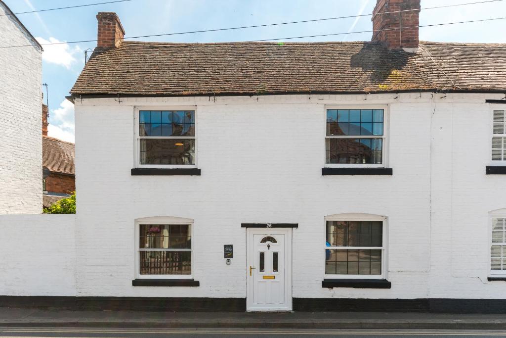 a white house with a white door and windows at Bard's Cottage in Alcester