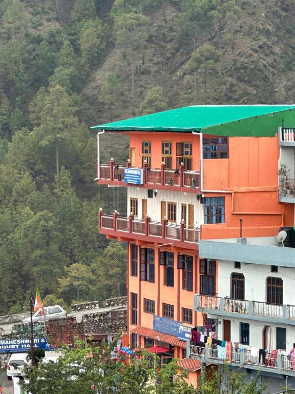 een oranje gebouw met een groen dak op een berg bij Hotel Maheshwari & Banquet Hall in Chamba