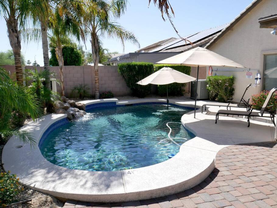 a small swimming pool with an umbrella and a table and an umbrella at Everything New! Ball Park Oasis With Heated Pool in Goodyear