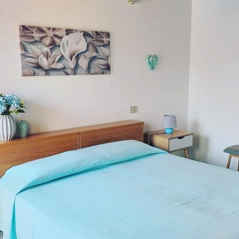 um quarto com uma cama azul com um quadro na parede em Affitto camera il corbezzolo em Palmas Arborea