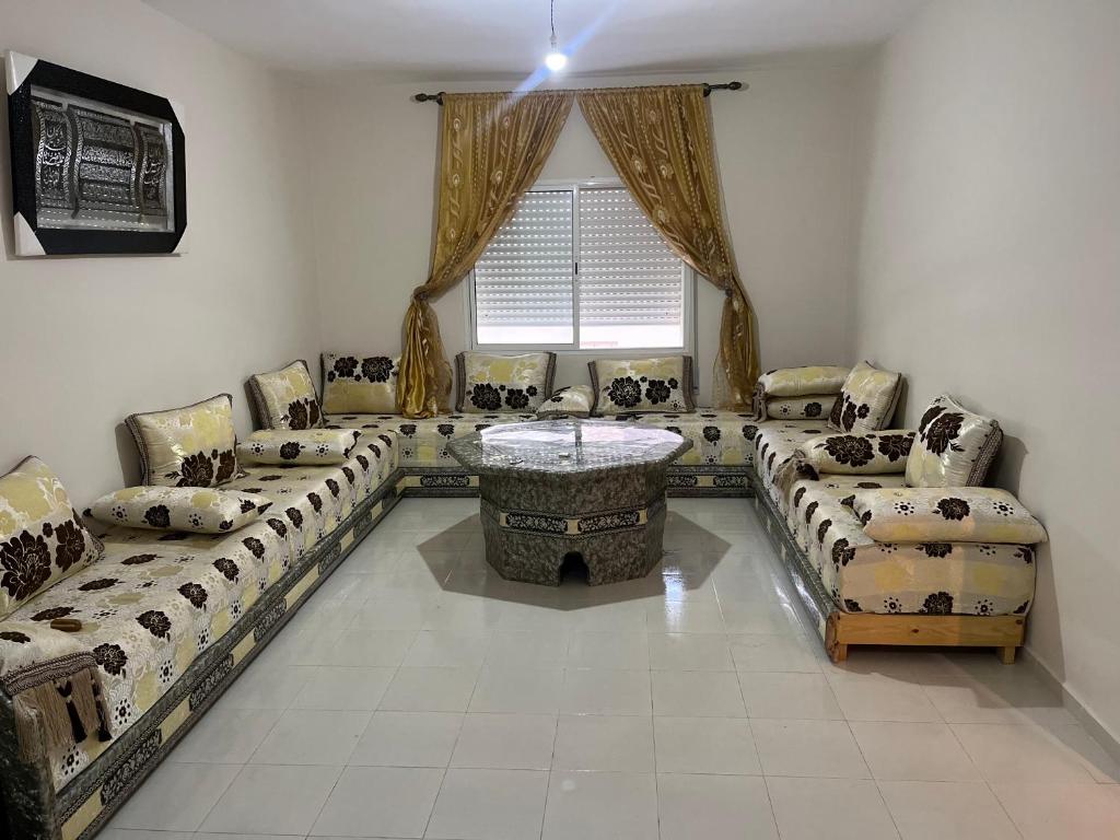 ein Wohnzimmer mit Sofas, einem Tisch und einem Fenster in der Unterkunft Appartement saidia 2 chambres in Saidia 