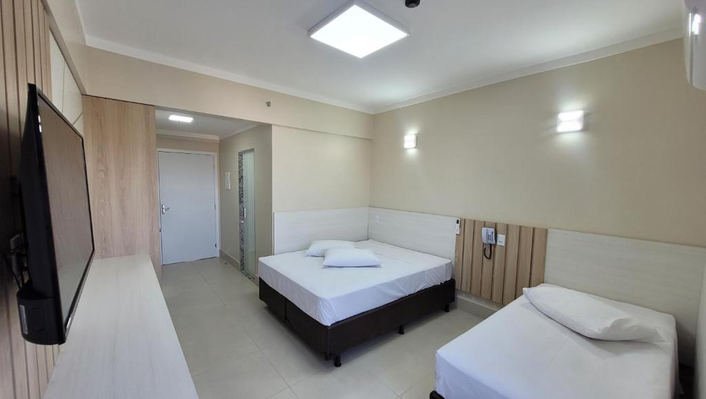a small room with two beds and a television at Spazzio Diroma Hospedagem com acesso gratuito no Acqua Park in Caldas Novas