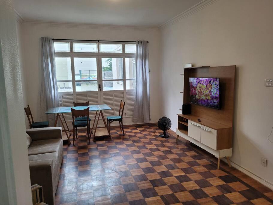 ein Wohnzimmer mit einem Tisch und einem TV in der Unterkunft Suhcasa Leme Beach 3 quartos in Rio de Janeiro