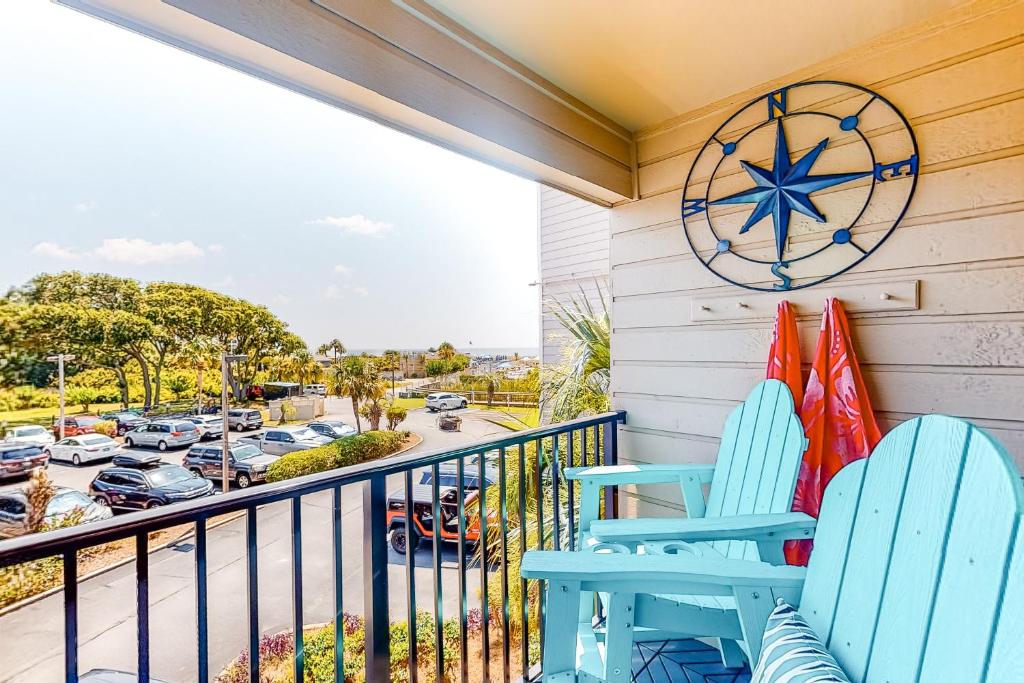 a balcony with two blue chairs and surfboards at Hilton Head Beach & Tennis Unit B222 in Hilton Head Island