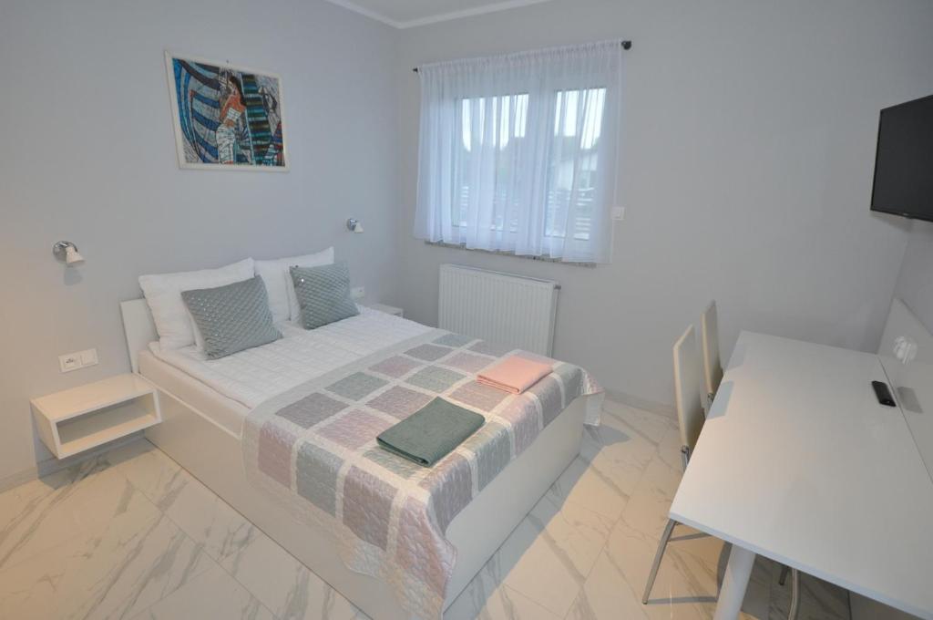 a white bedroom with a bed and a window at APARTAMENTY POD ŻAGLAMI MIELENKO in Mielenko