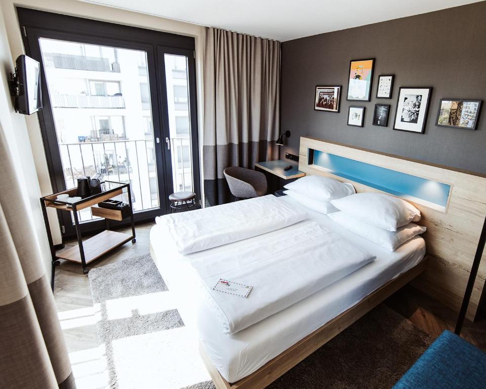 um quarto com uma cama grande e uma janela grande em Emma by Schulz Hotel Berlin Friedrichshain em Berlim