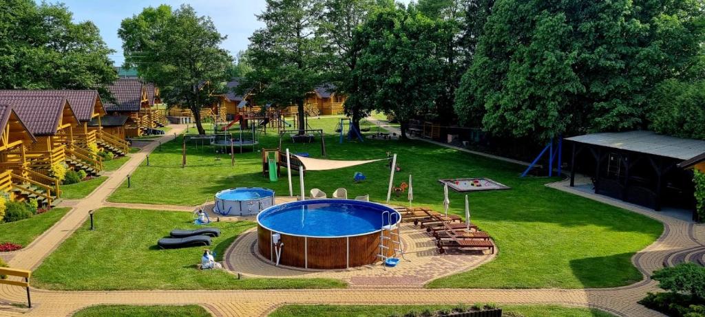 un parque infantil al aire libre con una gran piscina en el césped en Domki i pokoje "ZIELONA PRZYSTAŃ" en Sztutowo