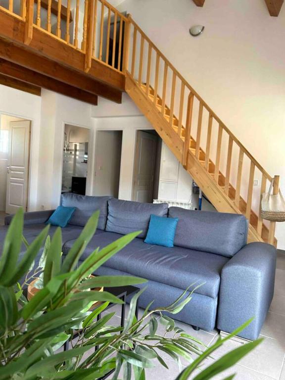a living room with a blue couch and a staircase at Maison piscine &amp; spa Vallon Pont d&#39;Arc in Vallon-Pont-dʼArc