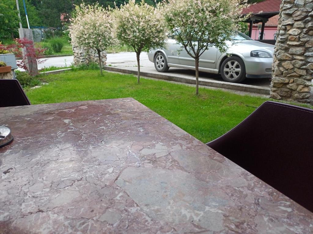 Vila Nenad Ovčar banja في تشاتشاك: طاولة حجرية في ساحة مع سيارة