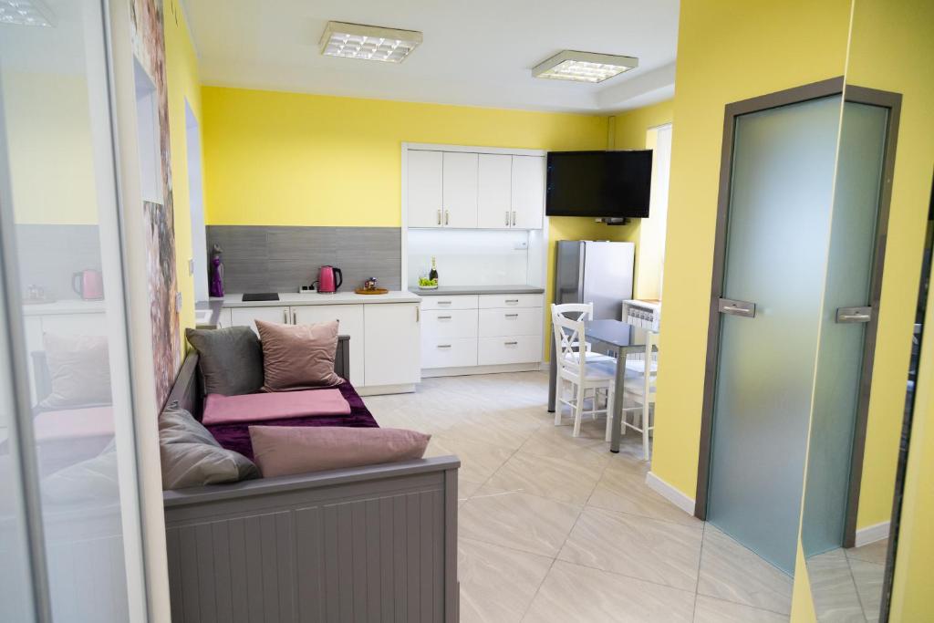 a kitchen with yellow walls and a couch in a room at Apartament przy Rynku in Ostrowiec Świętokrzyski