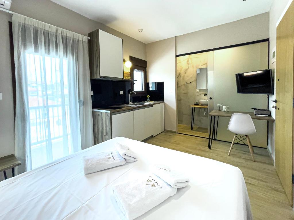 a hotel room with a white bed and a kitchen at ATHONITE all seasons luxury suites in Ierissos