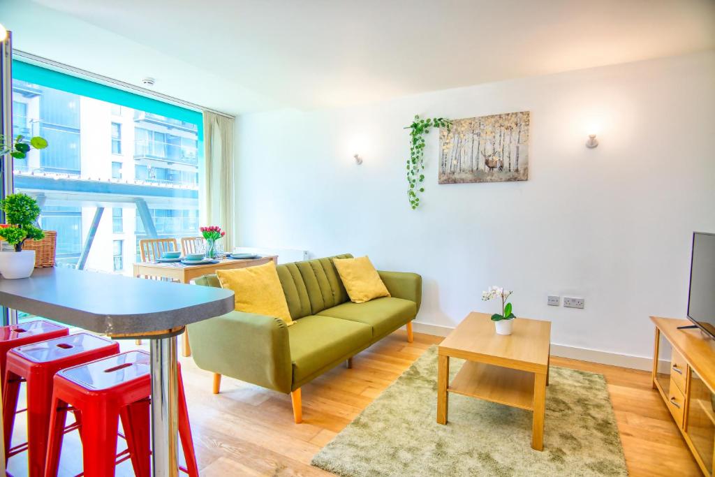 sala de estar con sofá verde y mesa en Your gateway to London & Heathrow, Stylish flat near station en Hayes