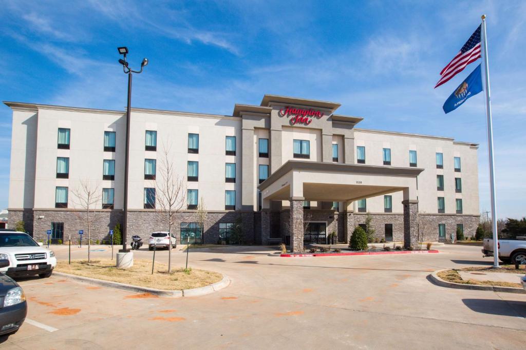 a hotel with an american flag in front of it at Hampton Inn El Reno Ok in El Reno