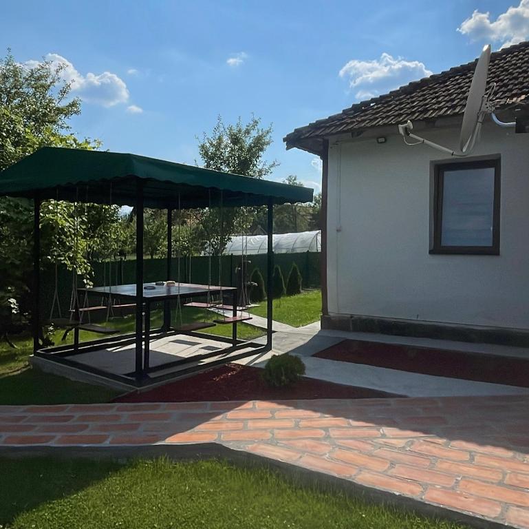 un patio con una mesa de picnic y una sombrilla verde en Vikendica Cerović, en Kraljevo