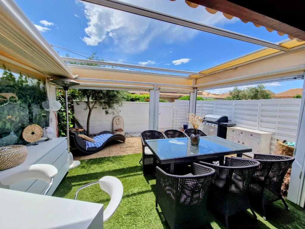 un patio avec une table et des chaises sur l'herbe dans l'établissement Villa à deux pas de la plage Richelieu, au Cap d'Agde