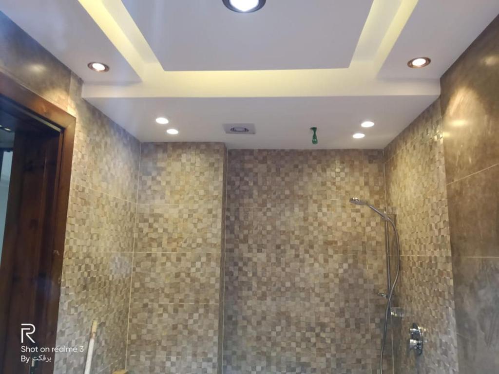 uma casa de banho com um chuveiro e paredes em azulejo em elite department em Kafr al Muşayliḩah