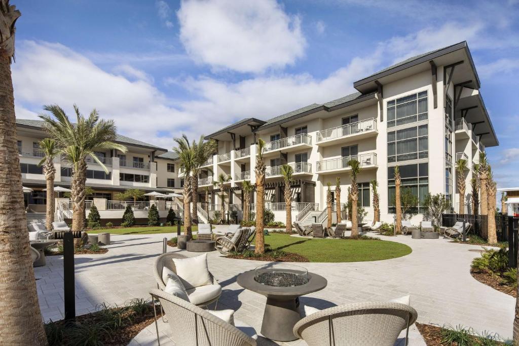 Embassy Suites St Augustine Beach Oceanfront Resort في ساينت أوغستين بيتش: ساحة مع كراسي وطاولة أمام المبنى