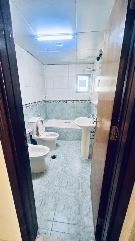 a bathroom with two toilets and a tub and a sink at Near Alain Main Bus Stop, in Al 'Ayn