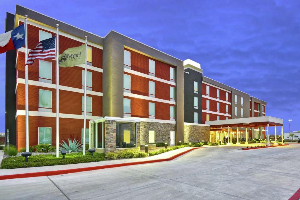 een weergave van een hotel met vlaggen op een parkeerplaats bij Home2 Suites by Hilton Brownsville in Brownsville