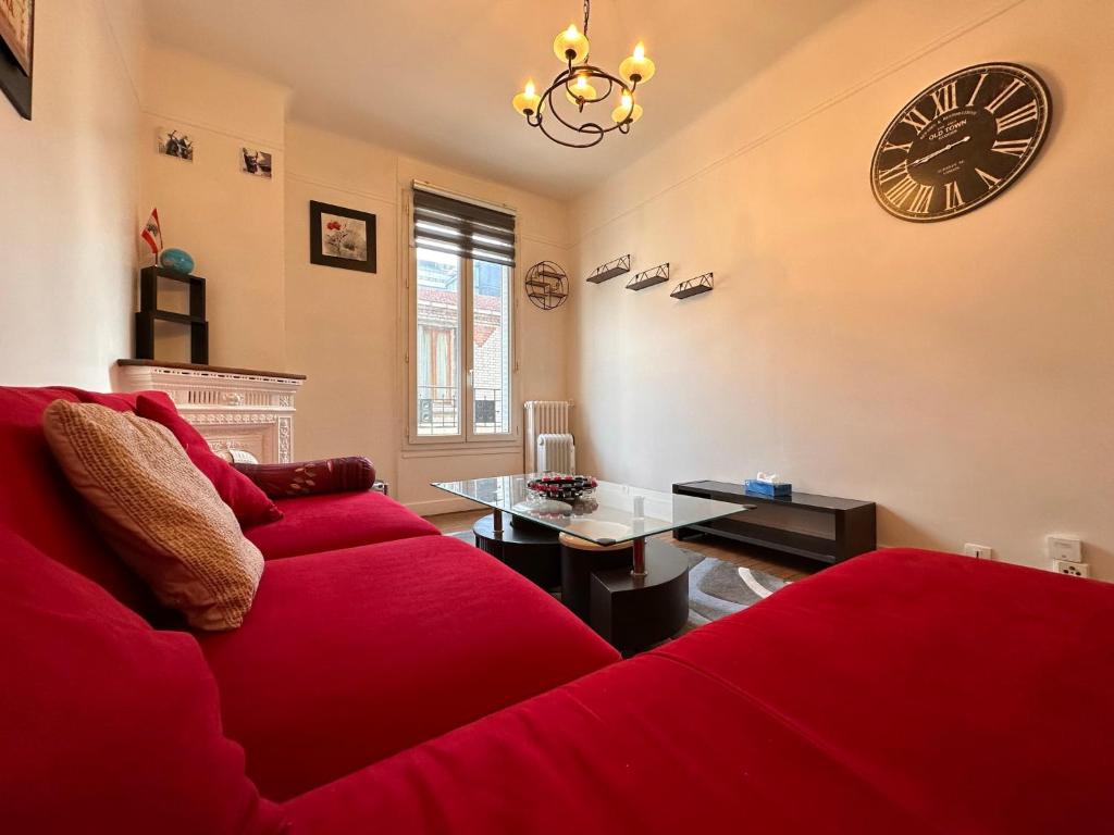 - un salon avec un canapé rouge et une horloge murale dans l'établissement Grand Appt' * Cosy * Proche Paris, à Bagneux