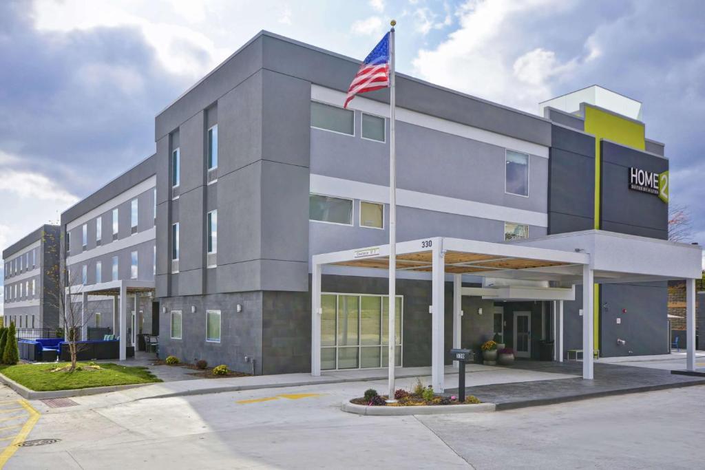 un bâtiment arborant un drapeau américain devant lui dans l'établissement Home2 Suites By Hilton Grand Rapids North, à Grand Rapids
