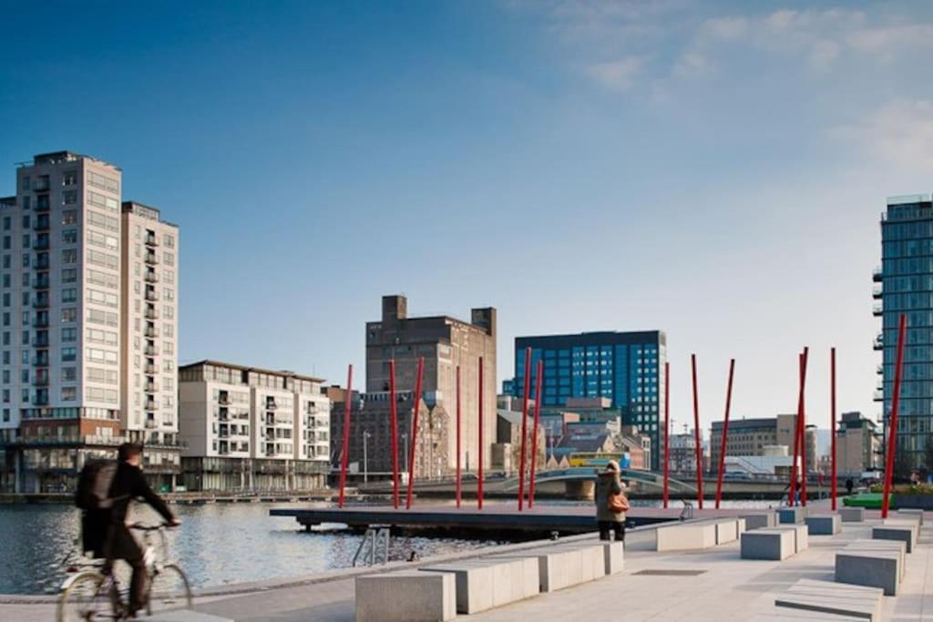 a person riding a bike in a city with buildings at Bright, modern apartment in Grand Canal Dock in Dublin