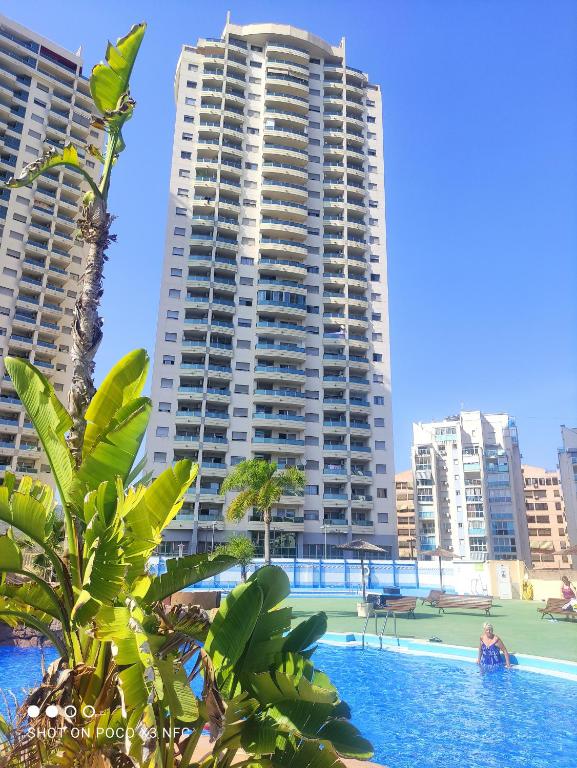 a woman in a swimming pool with two tall buildings at Bali Apartamento in Benidorm