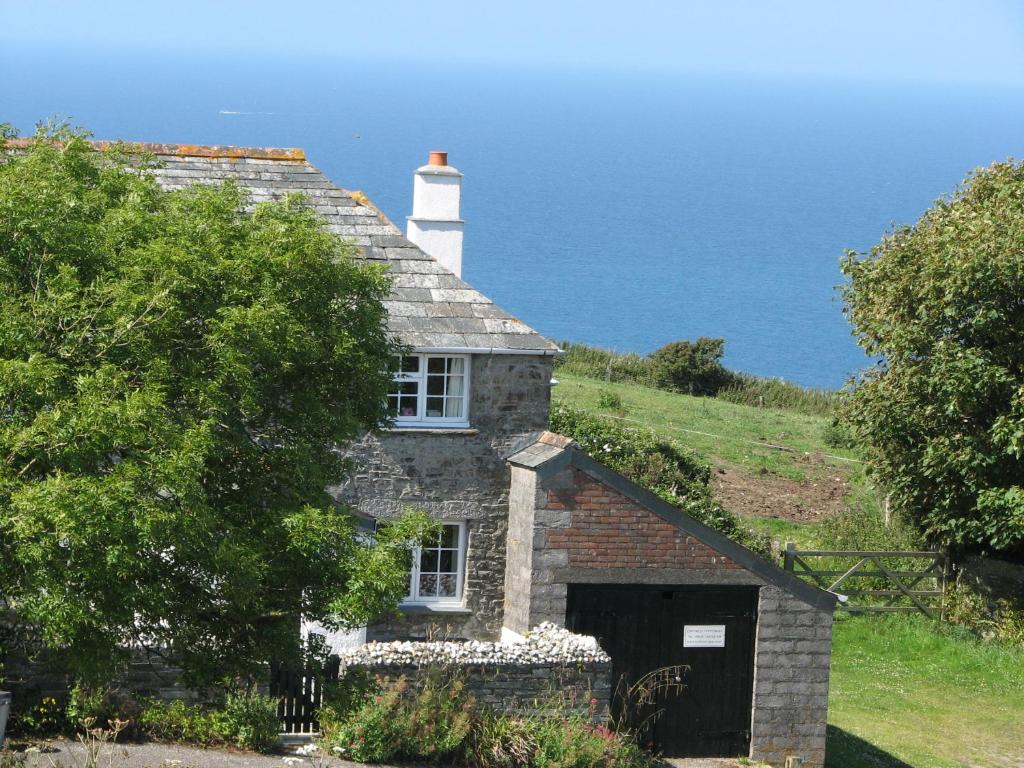 an old stone house with a lighthouse on top of it at Barton Cottage in Bude