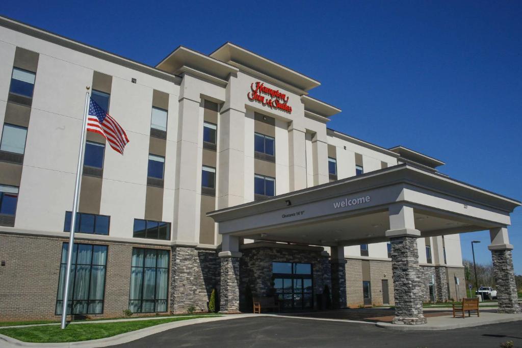 an exterior view of a hotel with an american flag at Hampton Inn & Suites Forest City in Forest City