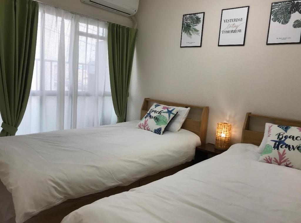 - une chambre avec 2 lits et une fenêtre avec des rideaux verts dans l'établissement happy house302 -駐車場無料, à Shimminatomachi