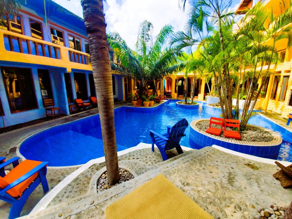 a resort swimming pool with palm trees and chairs at Reef View Pavilions - Villas & Condos in Lance aux Épines