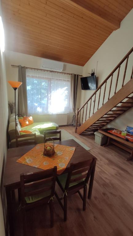 een woonkamer met een tafel en een trap bij Rigó Nyaralóház in Lakitelek