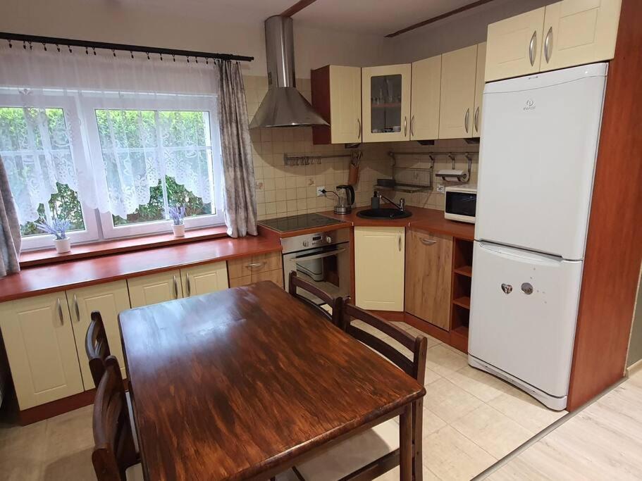 eine Küche mit einem Holztisch und einem weißen Kühlschrank in der Unterkunft Sztukateria Podgórzyn in Podgórzyn