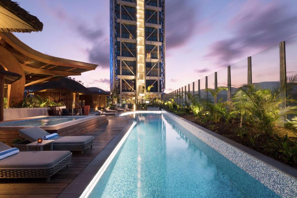 a swimming pool with lounge chairs and a building at Hilton Port Moresby Hotel & Residences in Port Moresby