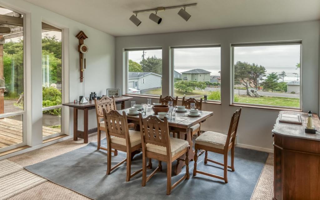a dining room with a table and chairs and windows at The Boat House in Yachats