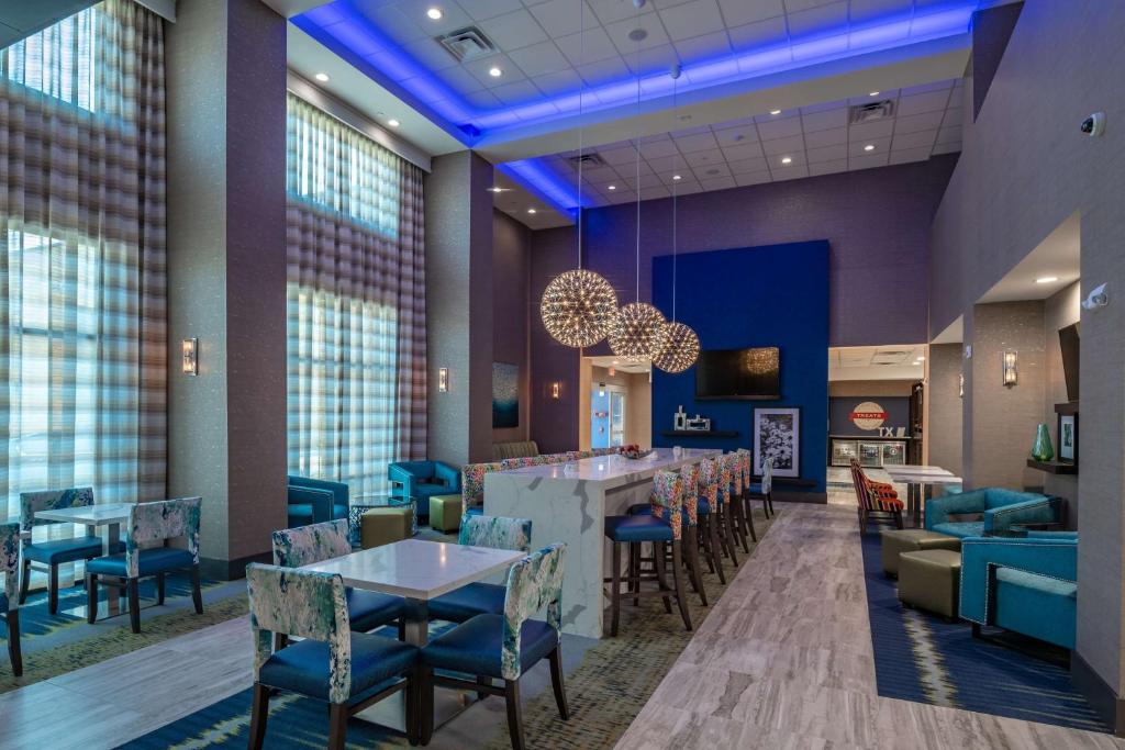 Un restaurante con mesas y sillas y un bar. en Hampton Inn & Suites Dallas/Plano Central, en Plano