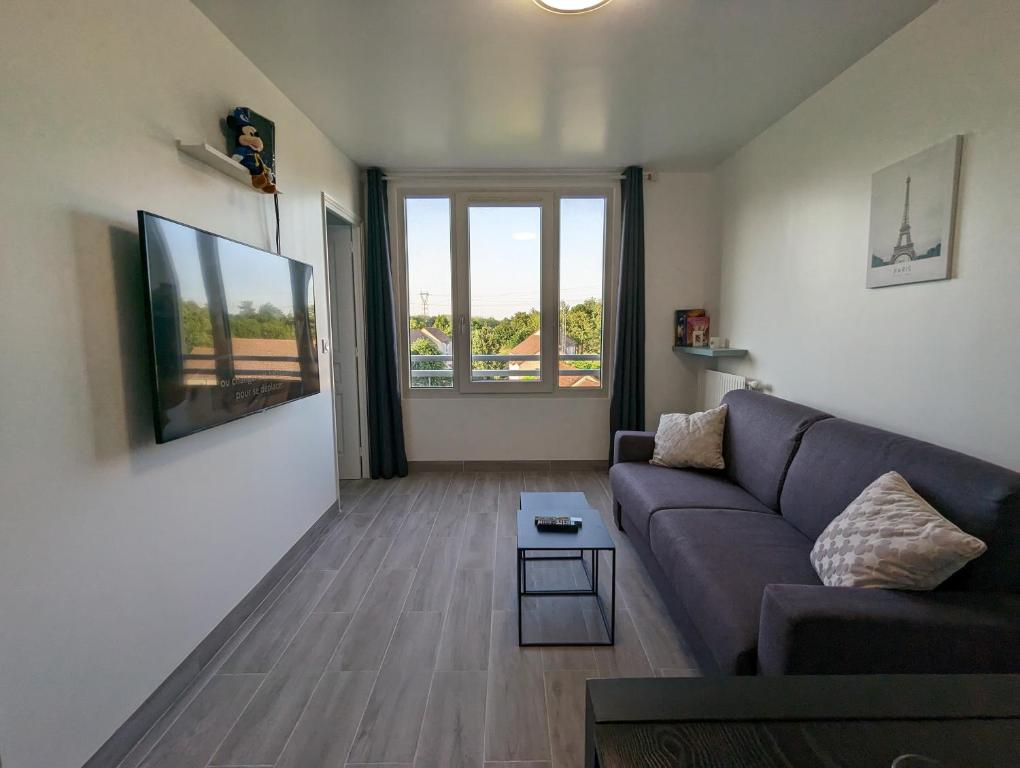 a living room with a couch and a table at Appart tout confort très proche RER A in Torcy