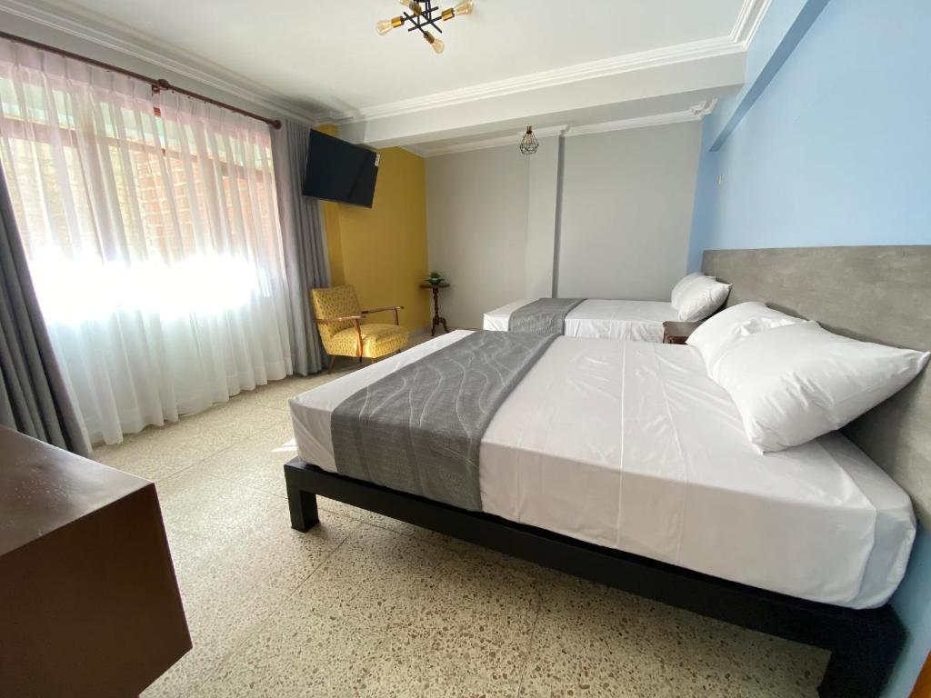 1 dormitorio con 2 camas y ventana en Izza Hotel, en Cochabamba