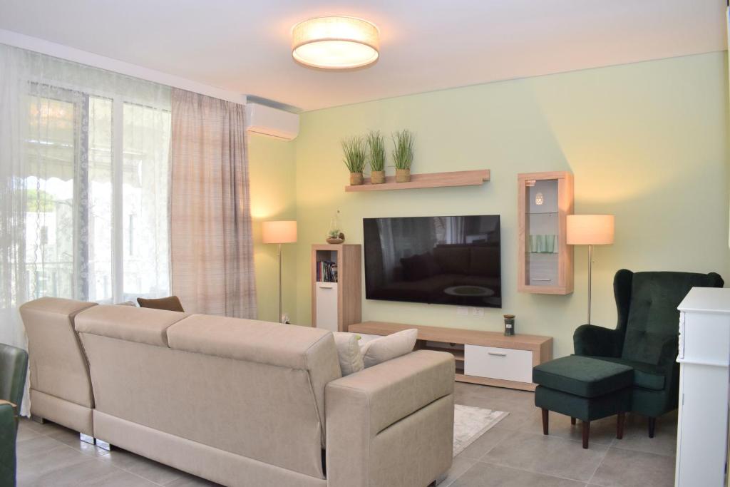 ein Wohnzimmer mit einem Sofa und einem Flachbild-TV in der Unterkunft Olive Tree Apartment - 290 in Mullini i Danit
