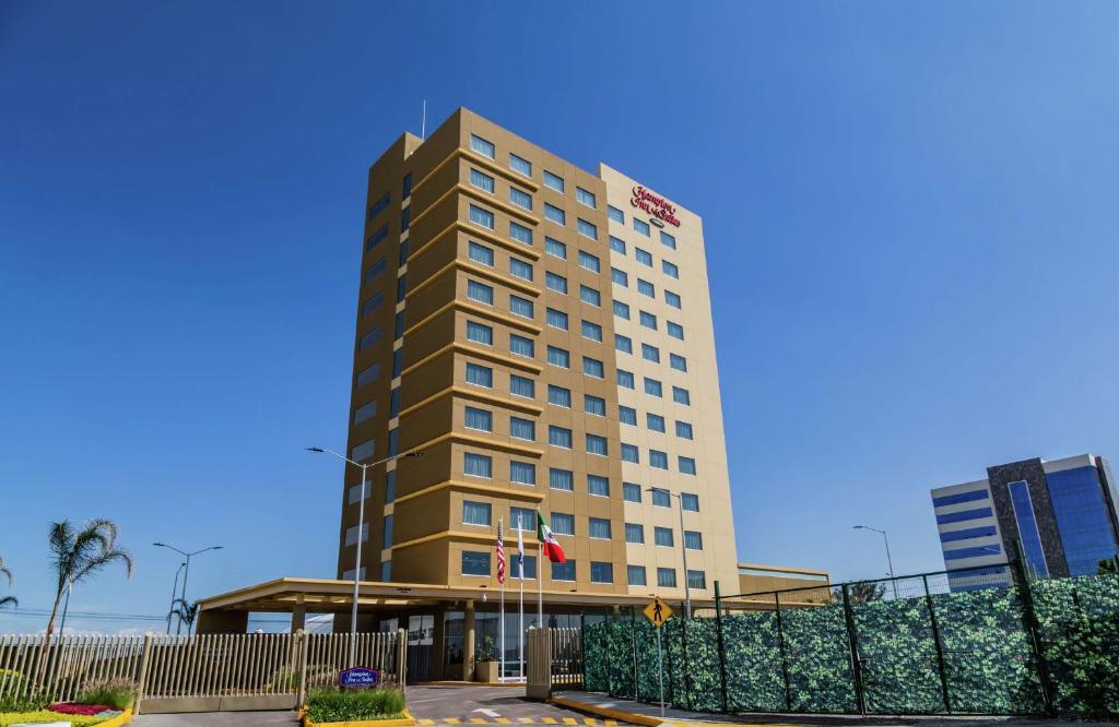 a tall building with a fence in front of it at Hampton Inn & Suites By Hilton Puebla in Puebla