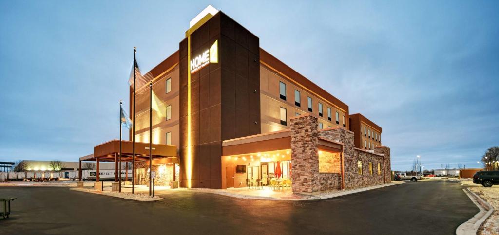 un grand bâtiment marron avec un parking dans l'établissement Home2 Suites By Hilton Beloit, à Beloit
