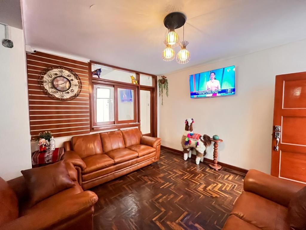 sala de estar con sofás de cuero y TV en Casa hospedaje Ingeniería - Lima, en Lima
